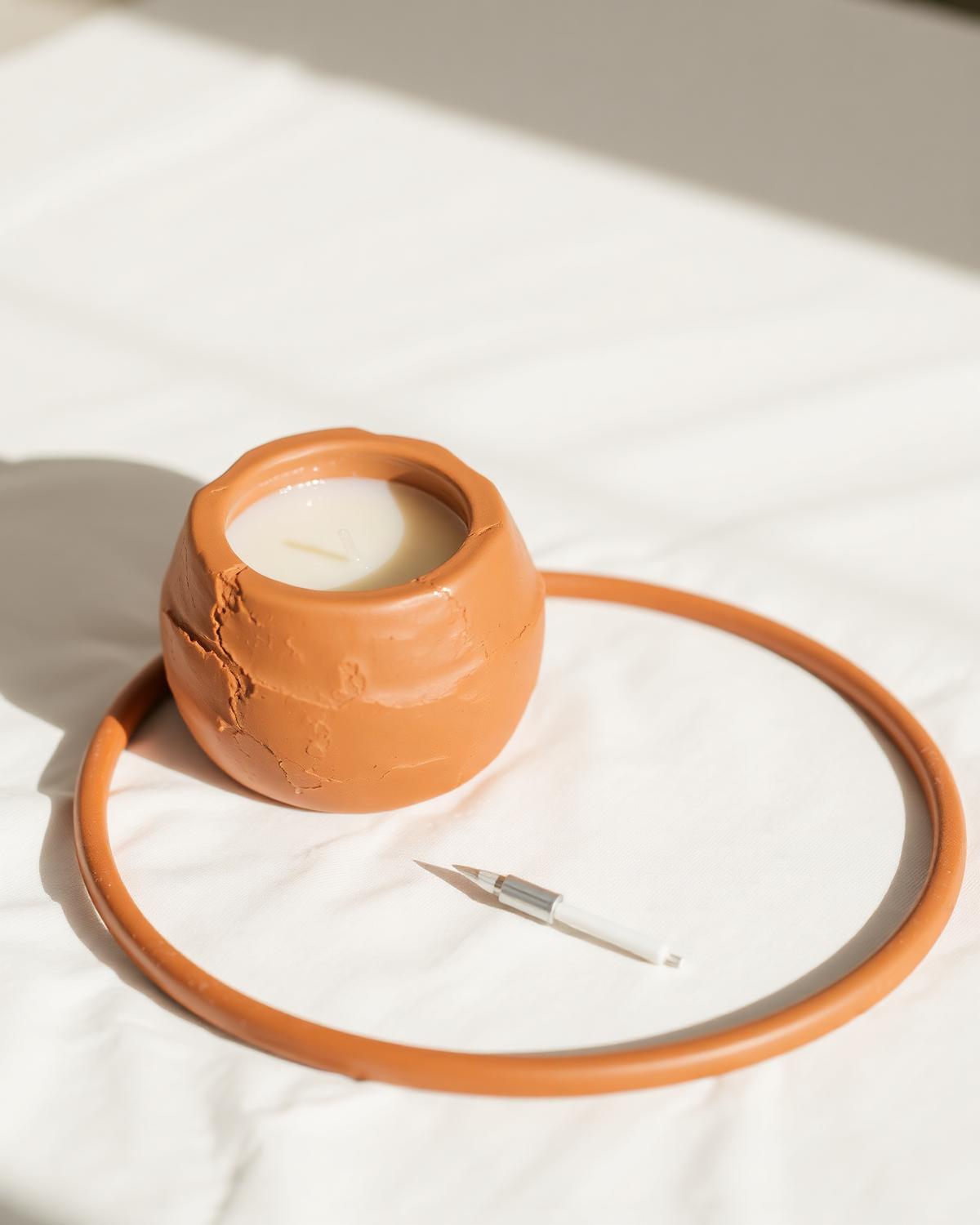Handmade terracotta clay candle holder with a soy candle in soft morning light